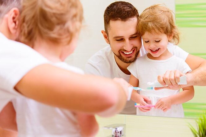 Familienvater und Tochter putzen Zähne zusammen im Bedezimmer